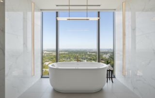 White Hydro Massage Products freestanding bathtub in a bright bathroom with large windows
